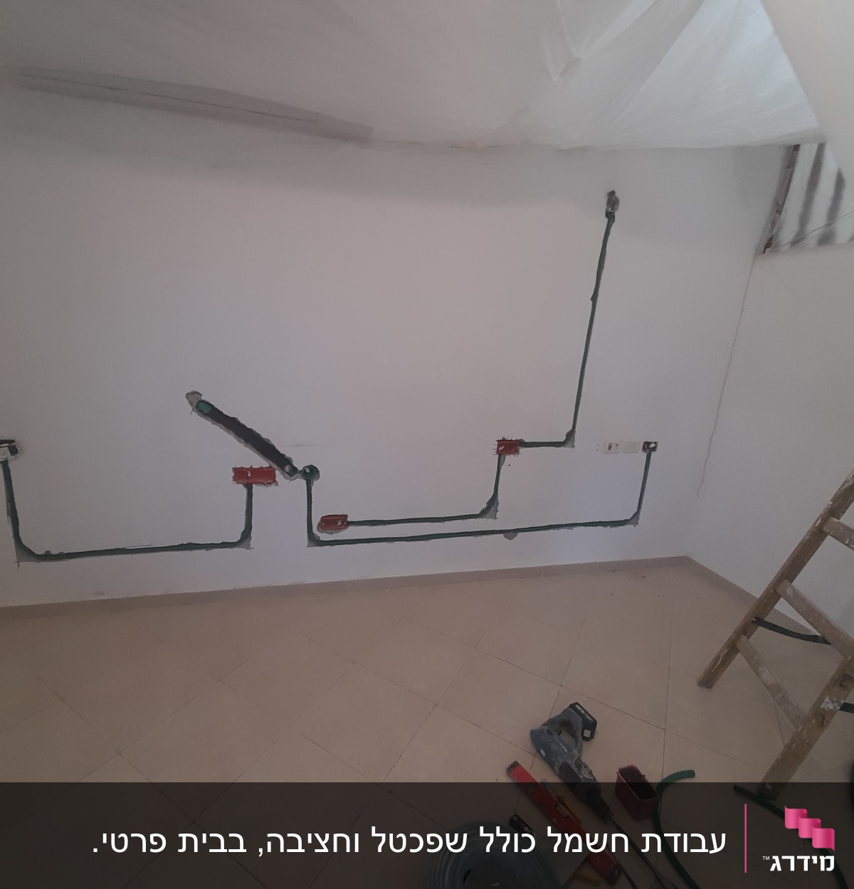 קיר גבס עם תעלות חשמל וכלי עבודה על הרצפה